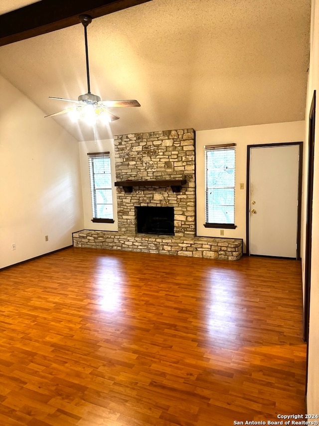 unfurnished living room featuring wood-type flooring, a textured ceiling, a healthy amount of sunlight, and beam ceiling