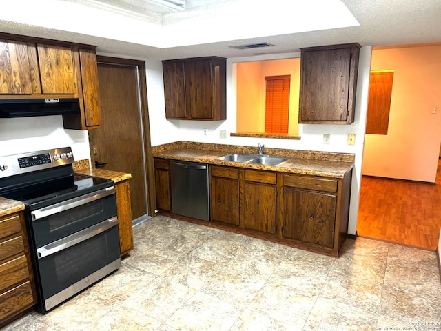 kitchen with a textured ceiling, light wood-type flooring, sink, and appliances with stainless steel finishes