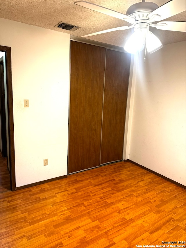 unfurnished bedroom featuring a textured ceiling, light wood-type flooring, a closet, and ceiling fan