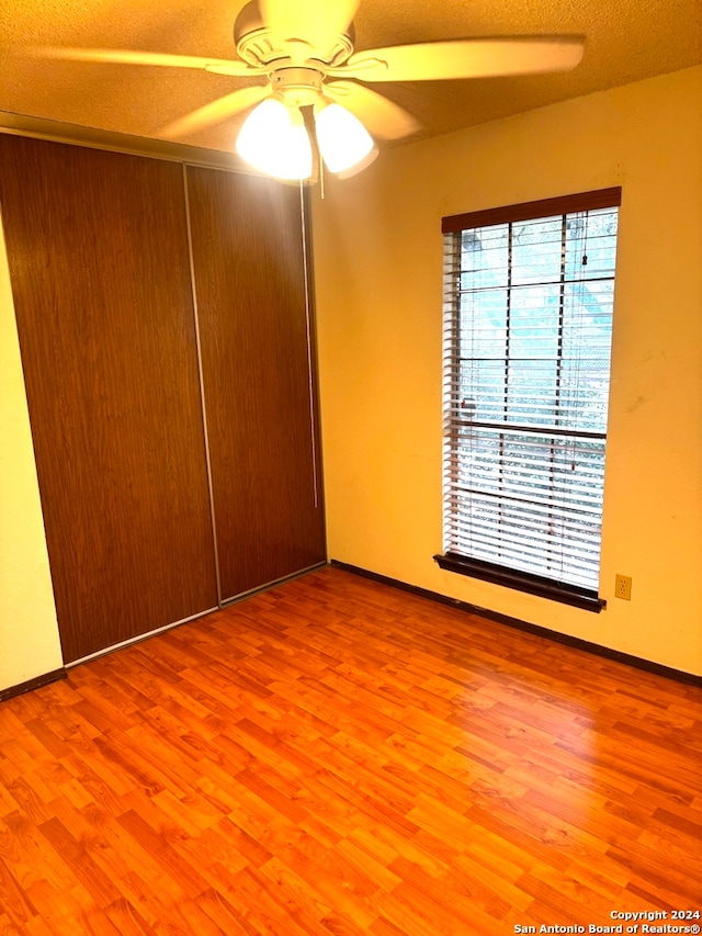 spare room with a textured ceiling, hardwood / wood-style flooring, and ceiling fan