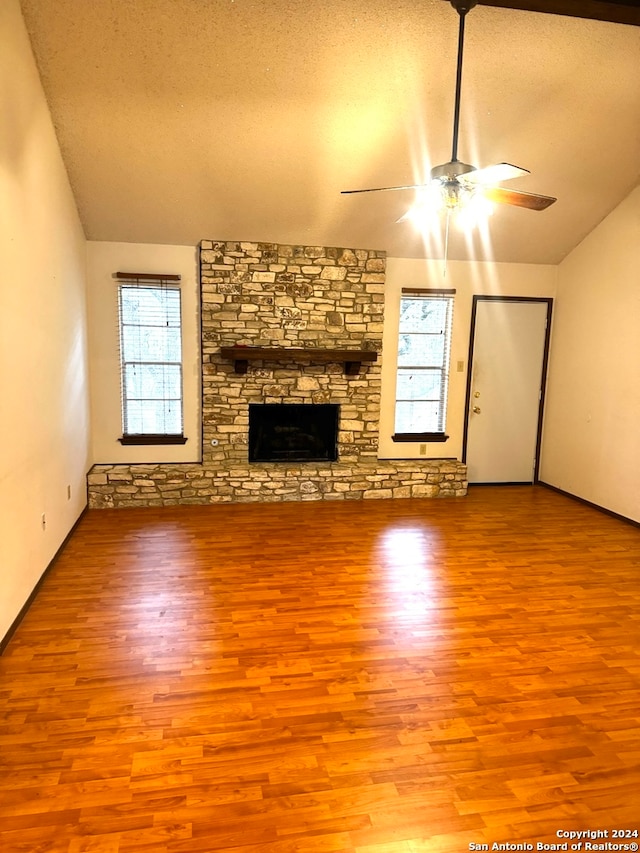 unfurnished living room featuring a textured ceiling, a healthy amount of sunlight, vaulted ceiling, and light wood-type flooring