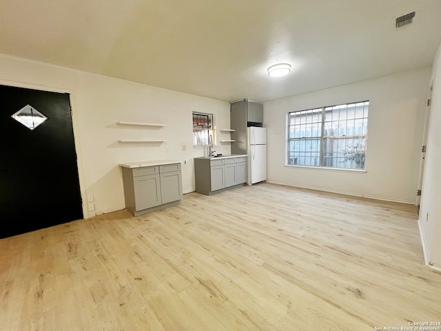 unfurnished living room with sink and light hardwood / wood-style floors