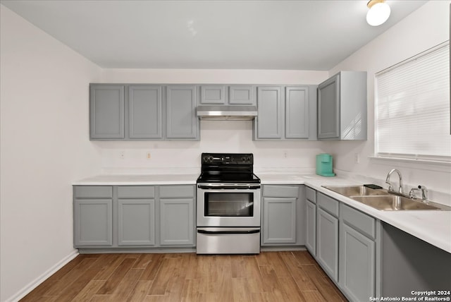 kitchen with light wood-type flooring, stainless steel electric range oven, gray cabinetry, and sink