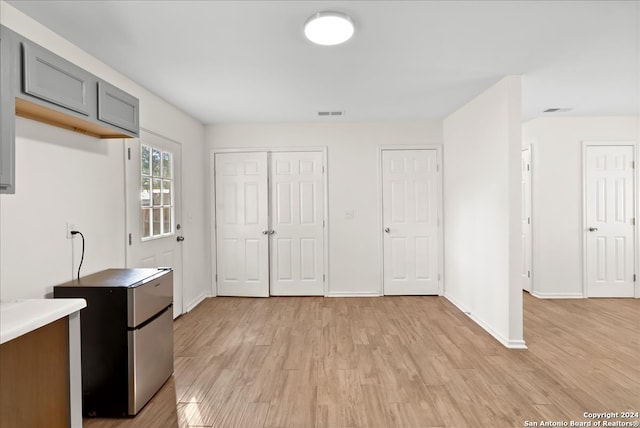 kitchen with gray cabinets, stainless steel fridge, and light wood-type flooring