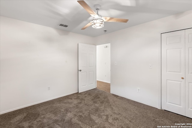 unfurnished bedroom featuring dark colored carpet, ceiling fan, and a closet