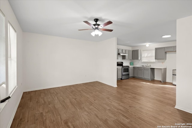 unfurnished living room with light wood-type flooring, ceiling fan, a healthy amount of sunlight, and sink