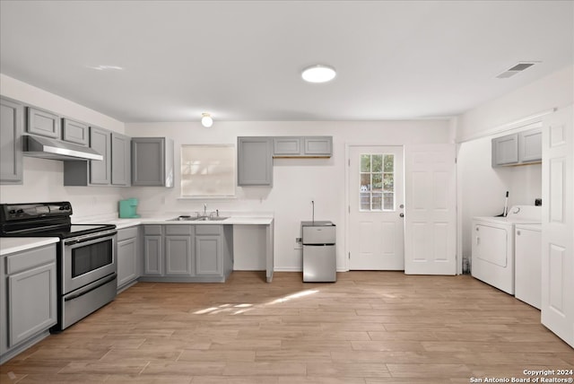 kitchen with sink, light hardwood / wood-style flooring, independent washer and dryer, gray cabinets, and appliances with stainless steel finishes