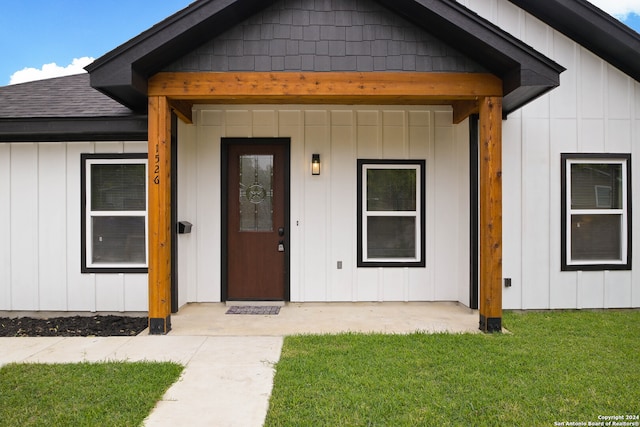 entrance to property with a porch and a yard