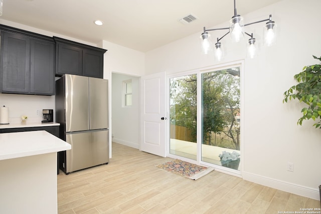 kitchen featuring stainless steel fridge, light hardwood / wood-style floors, and decorative light fixtures