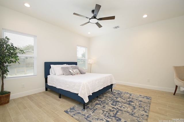 bedroom featuring multiple windows, light hardwood / wood-style floors, and ceiling fan