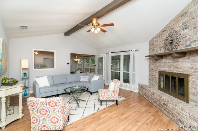 living room featuring vaulted ceiling with beams, ceiling fan, a fireplace, and light hardwood / wood-style flooring