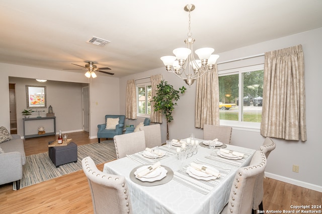 dining space with a healthy amount of sunlight, ceiling fan with notable chandelier, and wood-type flooring