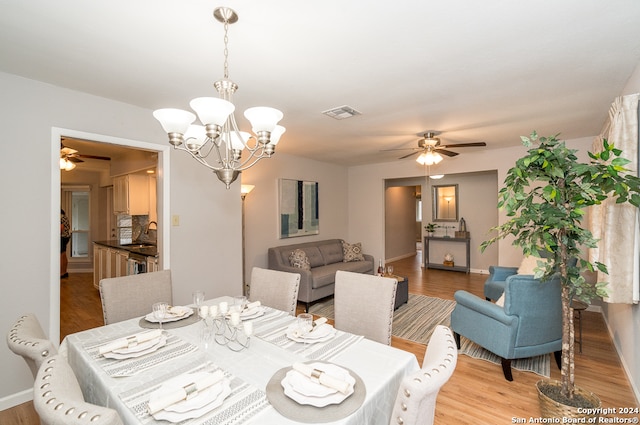 dining space featuring ceiling fan with notable chandelier, light hardwood / wood-style flooring, and sink