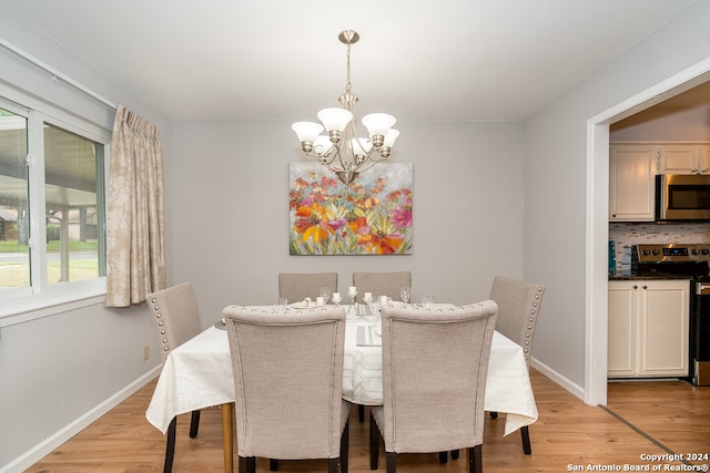 dining space with light wood-type flooring and an inviting chandelier