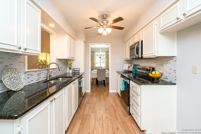 kitchen with stainless steel appliances, sink, dark stone countertops, white cabinets, and light hardwood / wood-style floors