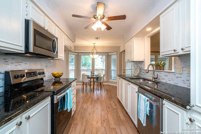 kitchen with stainless steel appliances, sink, light hardwood / wood-style flooring, white cabinetry, and hanging light fixtures