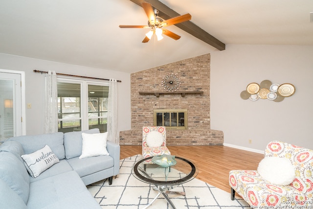 living room with lofted ceiling with beams, light hardwood / wood-style floors, a brick fireplace, and ceiling fan