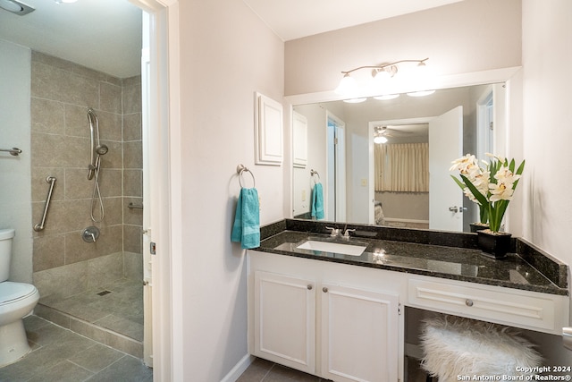 bathroom featuring tile patterned floors, vanity, tiled shower, and toilet