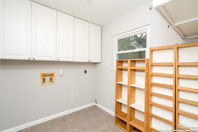 clothes washing area with hookup for an electric dryer, hookup for a washing machine, light tile patterned floors, and cabinets