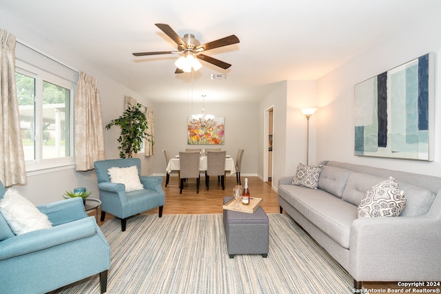 living room with wood-type flooring and ceiling fan with notable chandelier