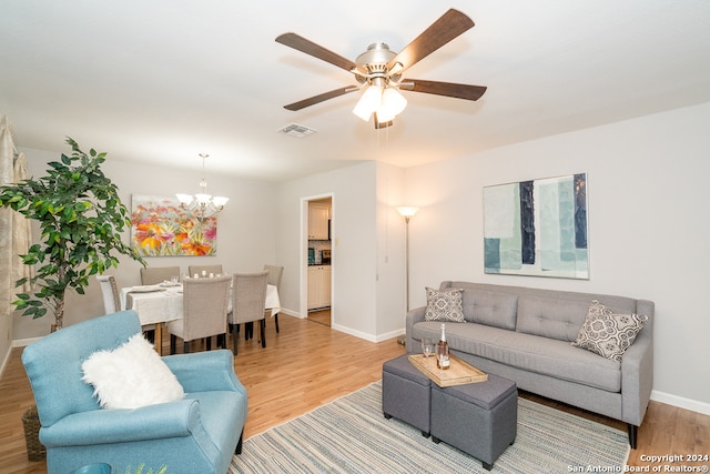 living room featuring ceiling fan with notable chandelier and hardwood / wood-style flooring