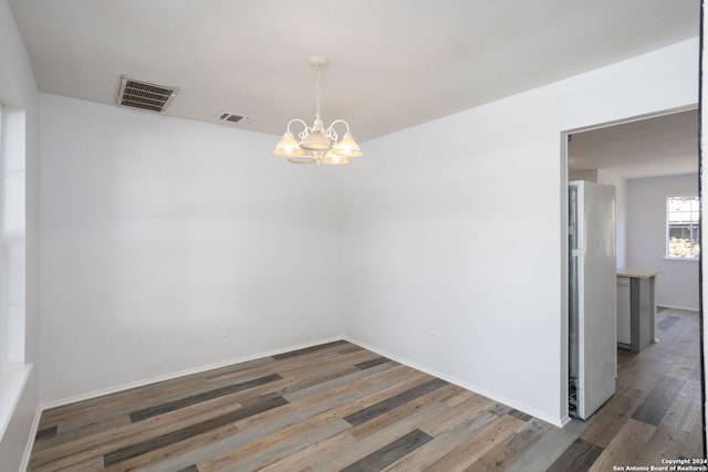 unfurnished dining area featuring dark hardwood / wood-style floors and an inviting chandelier