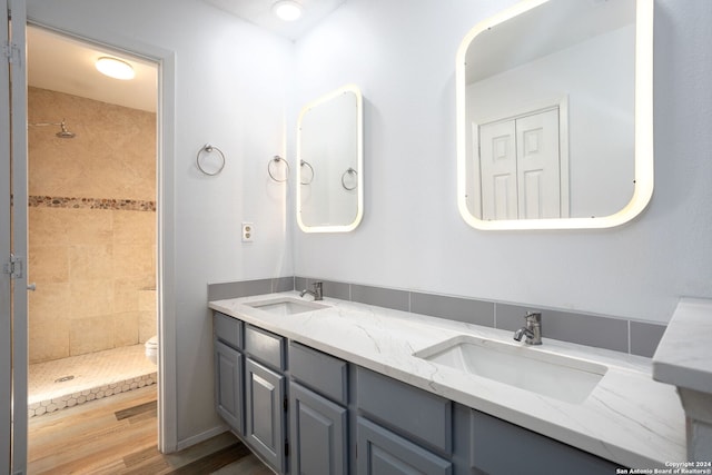 bathroom featuring vanity, toilet, wood-type flooring, and tiled shower