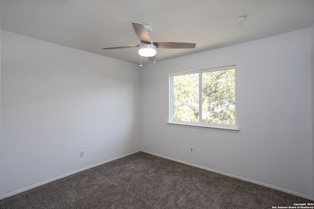 spare room with ceiling fan and dark carpet