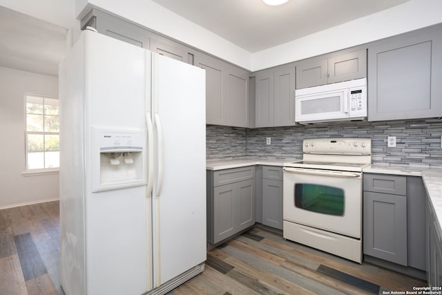 kitchen featuring white appliances, dark hardwood / wood-style floors, gray cabinets, and backsplash