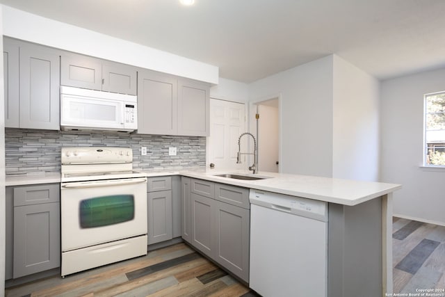 kitchen featuring kitchen peninsula, hardwood / wood-style floors, white appliances, and sink