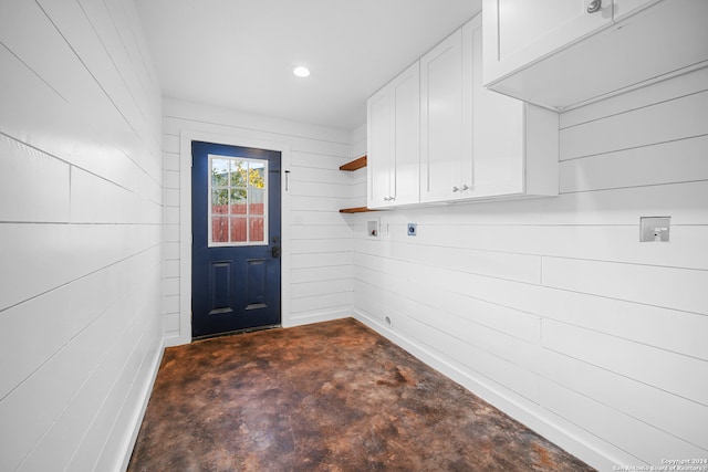 laundry room featuring electric dryer hookup, wood walls, and cabinets