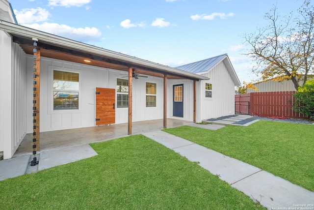 rear view of property with ceiling fan and a yard