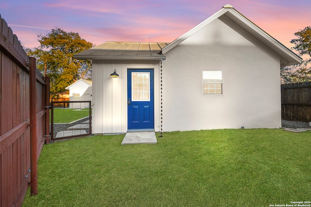 back house at dusk with a lawn