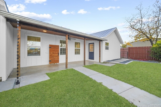 rear view of property with a lawn, ceiling fan, and a patio