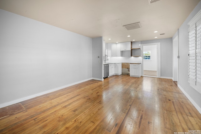 kitchen with dishwasher, light hardwood / wood-style floors, white cabinetry, and sink