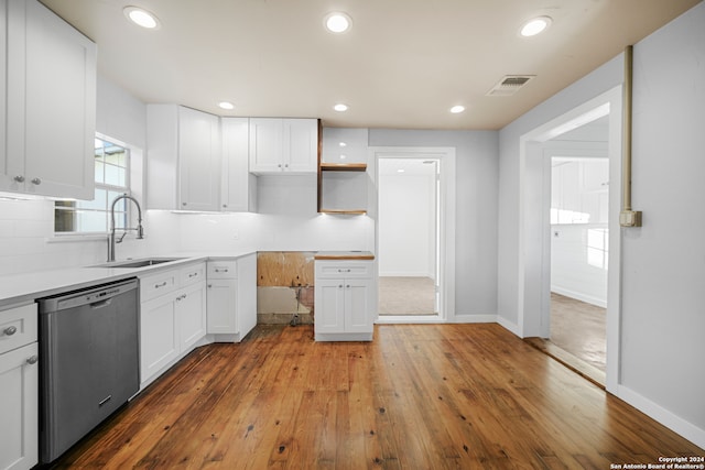 kitchen with white cabinetry, dishwasher, sink, wood-type flooring, and decorative backsplash