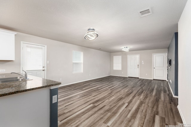 unfurnished living room featuring a textured ceiling, dark hardwood / wood-style floors, and sink