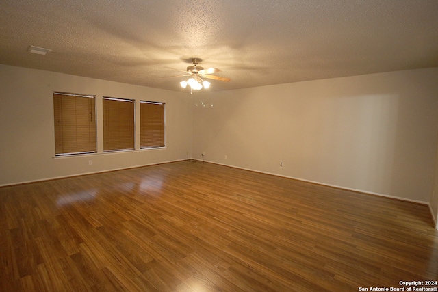 unfurnished room featuring dark hardwood / wood-style floors, ceiling fan, and a textured ceiling