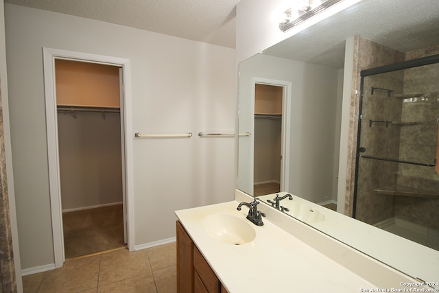 bathroom with tile patterned flooring, vanity, a textured ceiling, and a shower with shower door