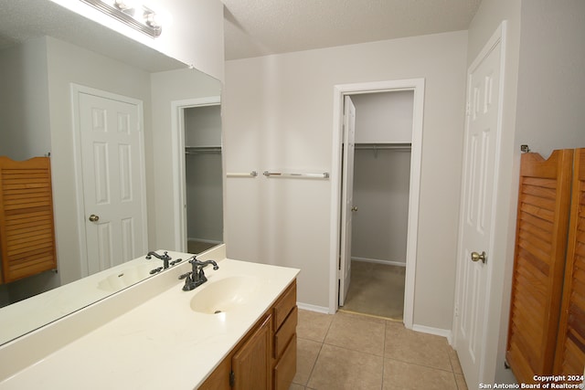 bathroom with tile patterned flooring, vanity, and a textured ceiling