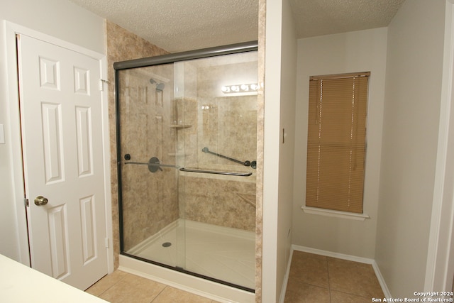 bathroom with tile patterned flooring, an enclosed shower, and a textured ceiling