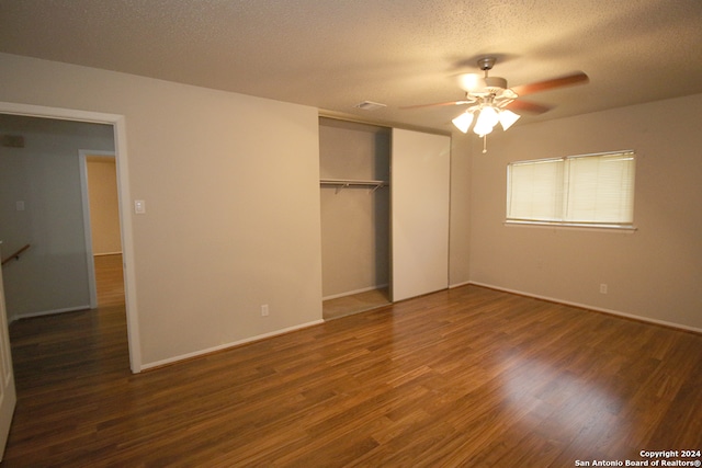 unfurnished bedroom with a textured ceiling, a closet, dark wood-type flooring, and ceiling fan