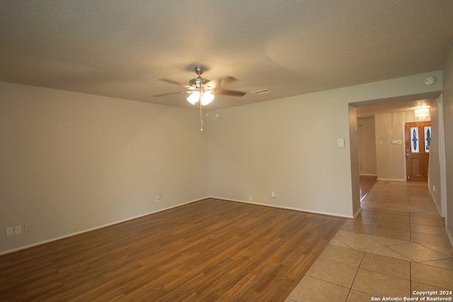 unfurnished room with ceiling fan, light hardwood / wood-style flooring, and a textured ceiling