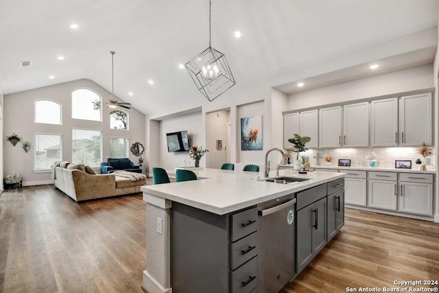 kitchen featuring stainless steel dishwasher, gray cabinets, a center island with sink, and sink