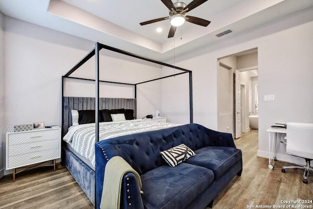 bedroom with wood-type flooring, a tray ceiling, and ceiling fan