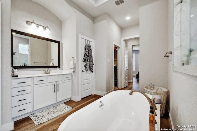 bathroom with hardwood / wood-style floors, vanity, and a bath