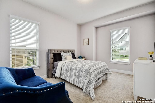 bedroom with light colored carpet and multiple windows