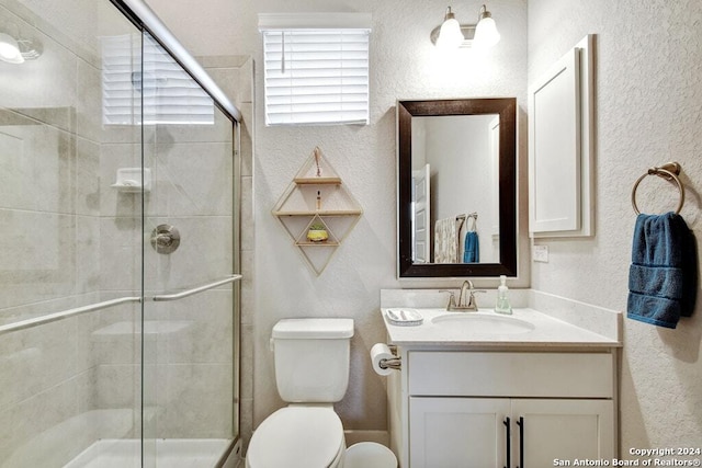 bathroom with vanity, a shower with shower door, and toilet