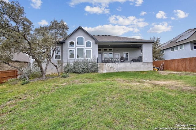 back of house with covered porch and a yard