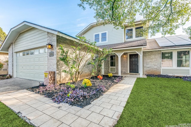 view of front of house featuring solar panels, a porch, a front yard, and a garage